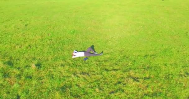 Niedriger Orbitalflug um den Menschen auf grünem Gras mit Notizblock auf gelbem Feld. — Stockvideo