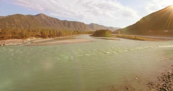 Vol à basse altitude au-dessus d'une rivière de montagne fraîche et rapide avec des rochers au soleil matin d'été. — Video