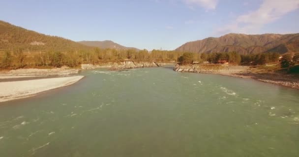 Vol à basse altitude au-dessus d'une rivière de montagne fraîche et rapide avec des rochers au soleil matin d'été. — Video