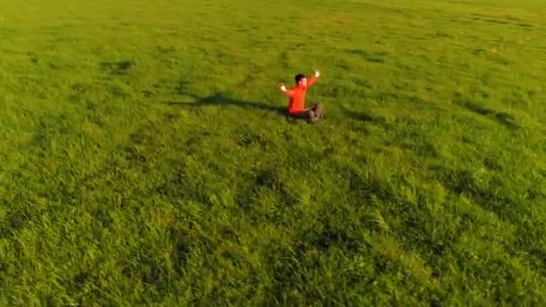 Vuelo radial de baja altitud sobre el hombre del yoga del deporte en hierba verde perfecta. Puesta de sol en montaña. — Vídeos de Stock