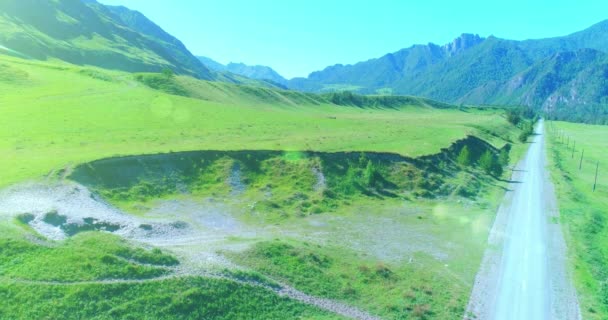 Luftlinie ländliche Bergstraße und Wiese an einem sonnigen Sommermorgen. Asphaltstraße und Fluss. — Stockvideo