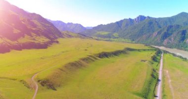 Güneşli yaz sabahında havadan kırsal dağ yolu ve çayır. Asfalt karayolu ve nehir.