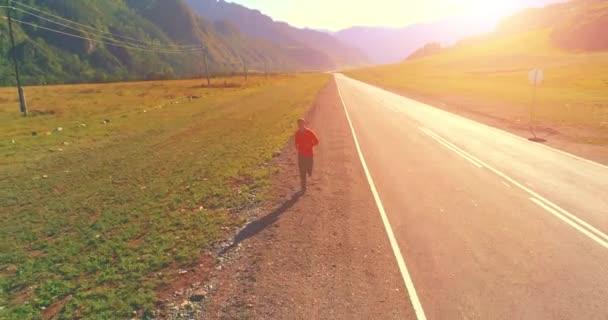 Vol à basse altitude devant un sportif sur une route asphaltée parfaite — Video