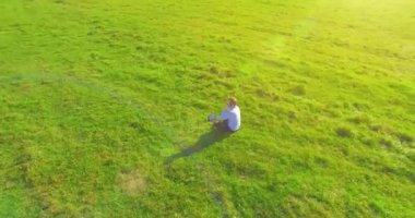 Yeşil çimlerin üzerinde sarı kırsal alanda not defteri olan bir adamın etrafında alçak yörünge uçuşları..