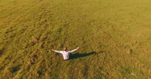 Vuelo orbital bajo alrededor del hombre sobre hierba verde con bloc de notas en el campo rural amarillo. — Vídeo de stock