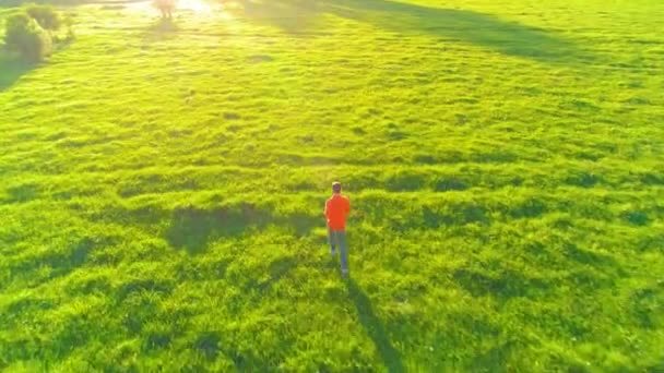 Let nad sportovní muž běží v dokonalé zelené trávě venkovských louka offroad. Západ slunce v horách — Stock video
