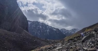 Yaz ya da sonbahar zamanı dağ vadisindeki destansı bulutların zamanı. Vahşi sonsuz doğa ve kar fırtınası gökyüzü. Kar zirvesinde güneş ışınları