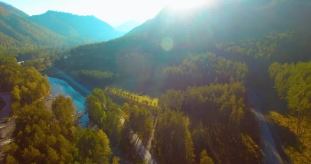 Vôo a meio do ar sobre o rio e o prado frescos da montanha na manhã ensolarada do verão. Estrada de terra rural abaixo. — Vídeo de Stock