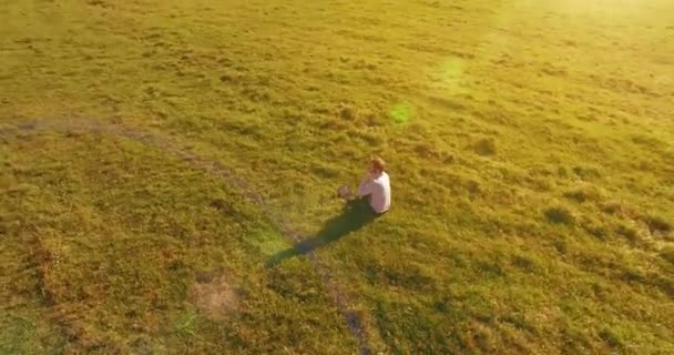 Низький орбітальний політ навколо людини на зеленій траві з блокнотом на жовтому сільському полі . — стокове відео