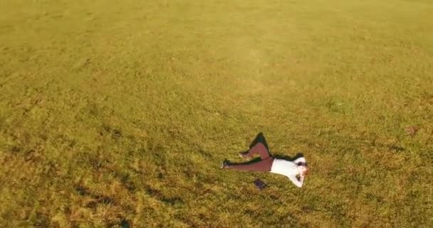 Vuelo orbital bajo alrededor del hombre sobre hierba verde con bloc de notas en el campo rural amarillo. — Vídeos de Stock