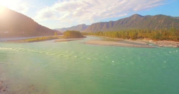 Vol à basse altitude au-dessus d'une rivière de montagne fraîche et rapide avec des rochers au soleil matin d'été. — Video