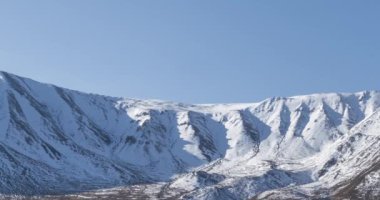 Güneşin kar dağının tepesinde kristal berrak gökyüzünde hareketinin zamanı. Sonbahar otlağında sarı çimenler. Vahşi sonsuz doğa..