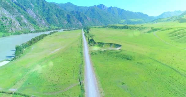 Flyg lantlig bergsväg och äng på solig sommarmorgon. Asfalterad motorväg och flod. — Stockvideo