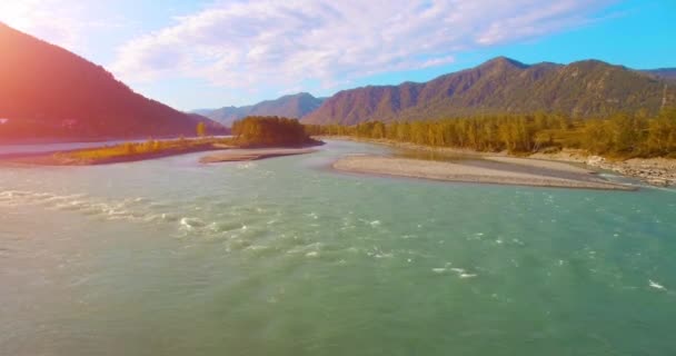 4k UHD aerial view. Low flight over fresh cold mountain river at sunny summer morning. Green trees and sun rays on horisont — Stock Video