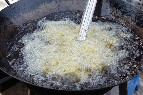 Boiling vegetable oil In a large iron pan