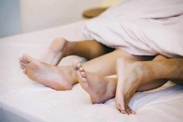Close up of male and female feet on a bed