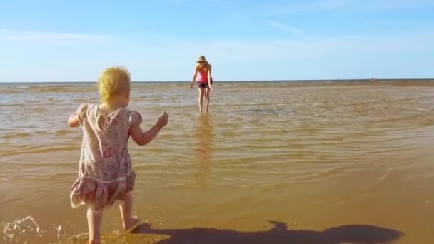 孩子跑到他的母亲通过水在海滩上 — 图库视频影像
