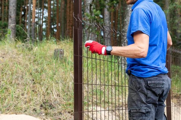 worker installing welded metal mesh fence