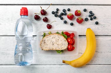 meyve ve su şişesini Beyaz ahşap masa üzerinde öğle yemeği kutusu