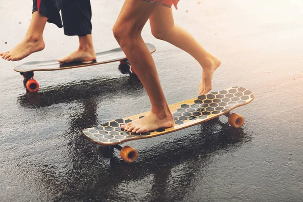 朋友骑 Longboards 在潮湿的城市街道日落 — 图库照片