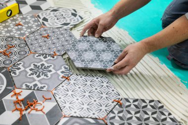 flooring - man laying hexagon tiles on the floor clipart