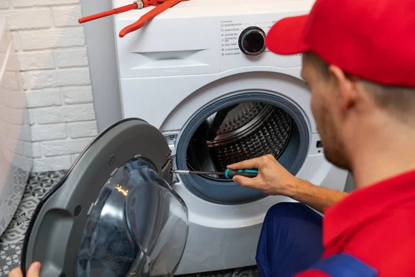 repairman with screwdriver repairing washing machine door