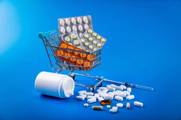 购物车充满药物和药物丸在蓝色背景 — 图库照片