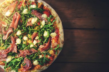 Prosciutto roka pizza kahverengi ahşap zemin üzerinde. üstten görünüm kopya alanı