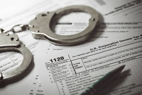 tax evasion concept - tax form 1120 and handcuffs