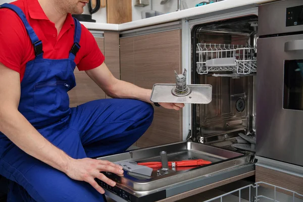 Ev aletleri bakım - tamirci kaldırma kirli bulaşık makinesi — Stok fotoğraf