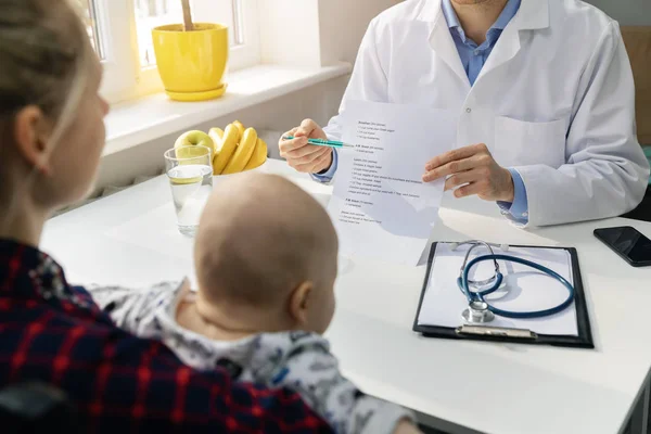 Nutricionista y madre joven con el bebé discutiendo un plan de nutrición equilibrada saludable en la oficina —  Fotos de Stock