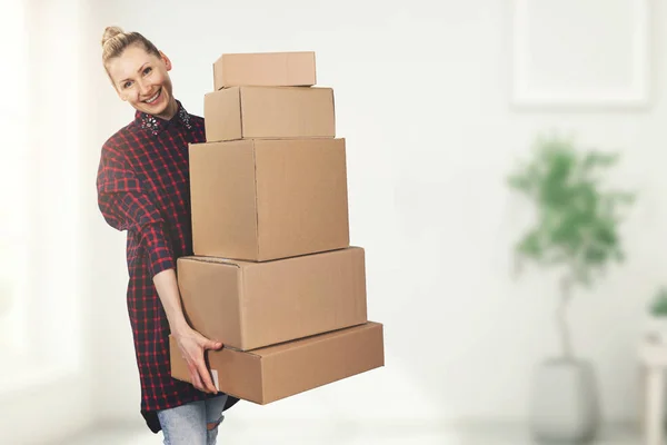 Donna felice in piedi nella nuova casa con scatole di appartenenza in mano — Foto Stock
