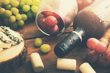 Üzüm ve mavi peynirli bir şişe kırmızı şarap.