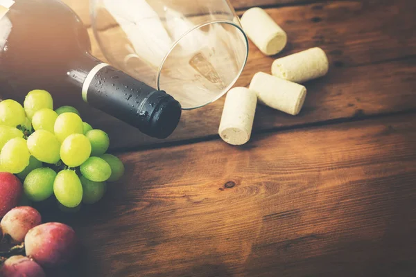 Garrafa de vinho tinto com vidro e uvas em fundo de madeira — Fotografia de Stock