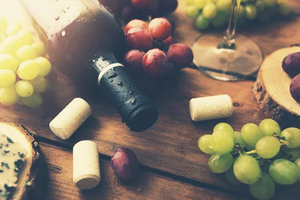 Garrafa de vinho tinto com uvas no fundo de madeira velho — Fotografia de Stock