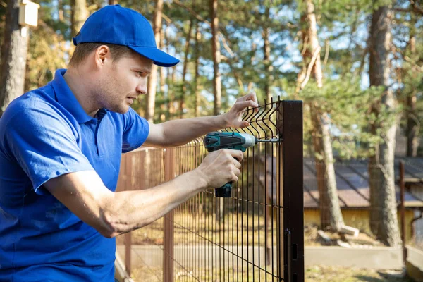 fencing services - worker installing welded metal mesh fence
