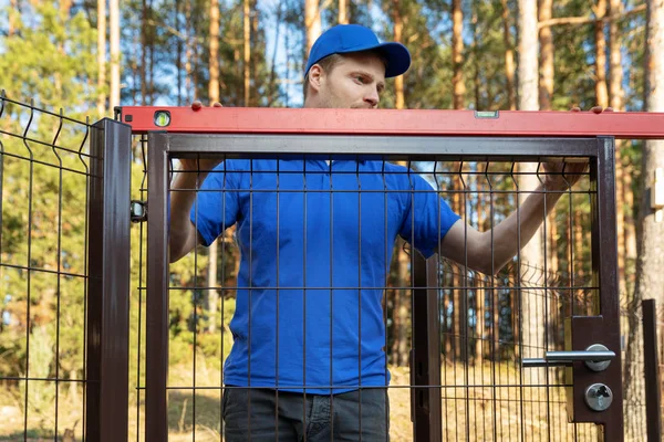 Hombre comprobar el nivel de las nuevas puertas de la cerca — Foto de Stock
