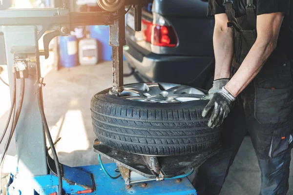 운행중인 차고 가장자리의 타이어를 교체하는 자동차 정비공 — 스톡 사진