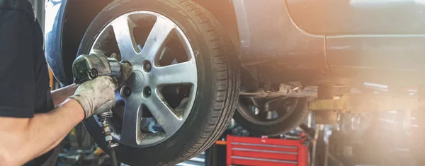 Car mechanic screwing the wheel at auto repair garage — Stock Photo, Image
