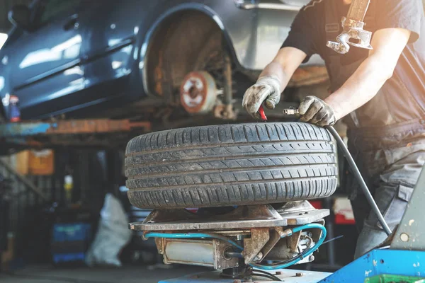 Mechanic fixing tire at car repair service — Stock Photo, Image