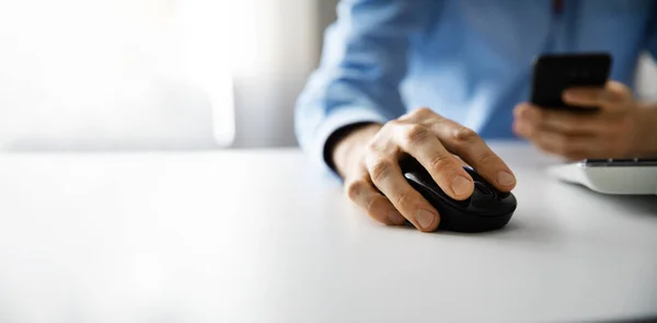 Homem trabalhando com computador desktop e usando telefone inteligente no escritório. espaço de cópia — Fotografia de Stock