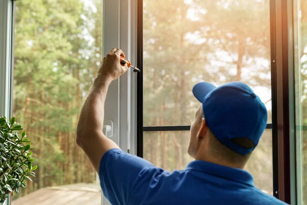 집 창에 모기 장 와이어 스크린을 설치하는 남자 스톡 사진