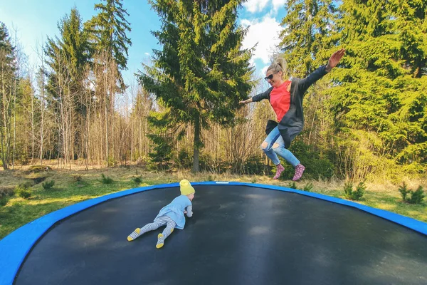 Mother and daughter jumping on trampoline outdoors — Stock Photo, Image