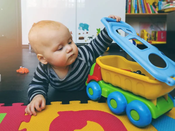 Bebek çocuk, evde yerde oyuncak arabasıyla oynuyor.