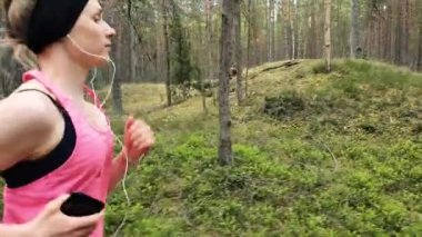 Genç fitness kadını çam ağacı orman yolunda koşuyor.