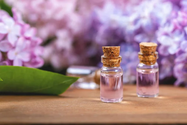 Lázeňská aromaterapie - lahvičky éterického oleje a šeříkové květy — Stock fotografie