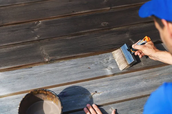 Homem restaura deck pátio de madeira com pintura protetora de madeira — Fotografia de Stock