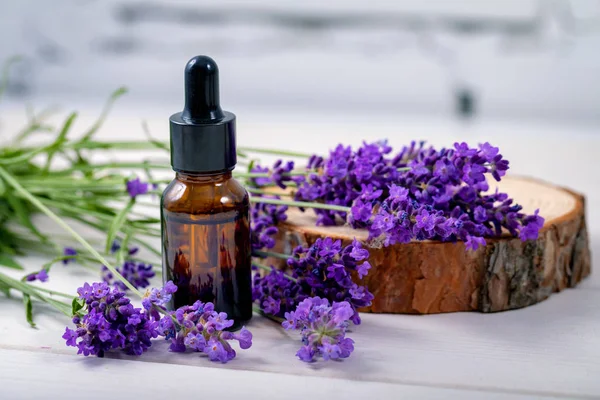 Levandulový bylinkový olej a květiny na dřevěném pozadí — Stock fotografie