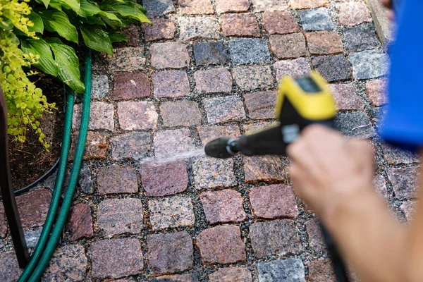 高圧で庭の石畳の経路を掃除する ストック写真