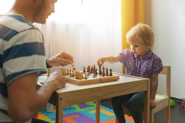 Juegos cerebrales - padre enseña a jugar ajedrez para su hijo en casa —  Fotos de Stock